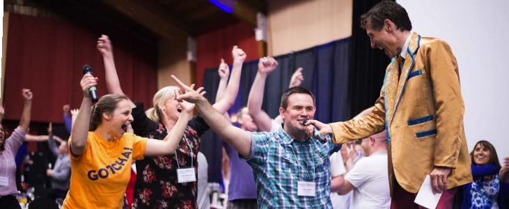A performer on stage with the crowd cheering during a Name That Tune corporate event