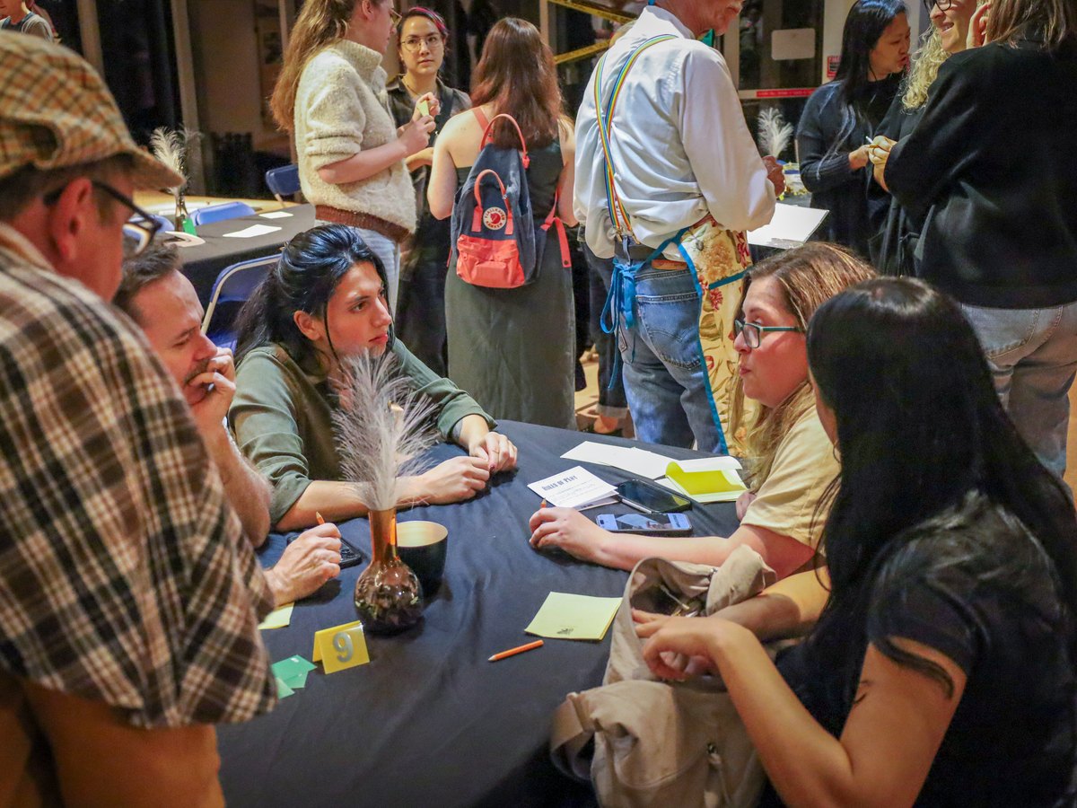 Guests at a table leaning in as the detective questions them during a Murder YOU Mystery at the Museum of Vancouver