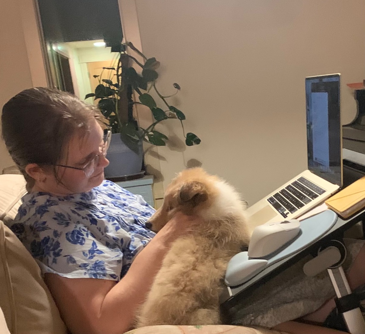 author petting dog while ignoring her computer